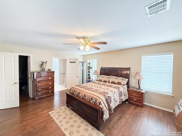 1185 County Road 7718, Devine, TX 78016 - bedroom with wood finished floors, ceiling fan, ensuite bath, and baseboards