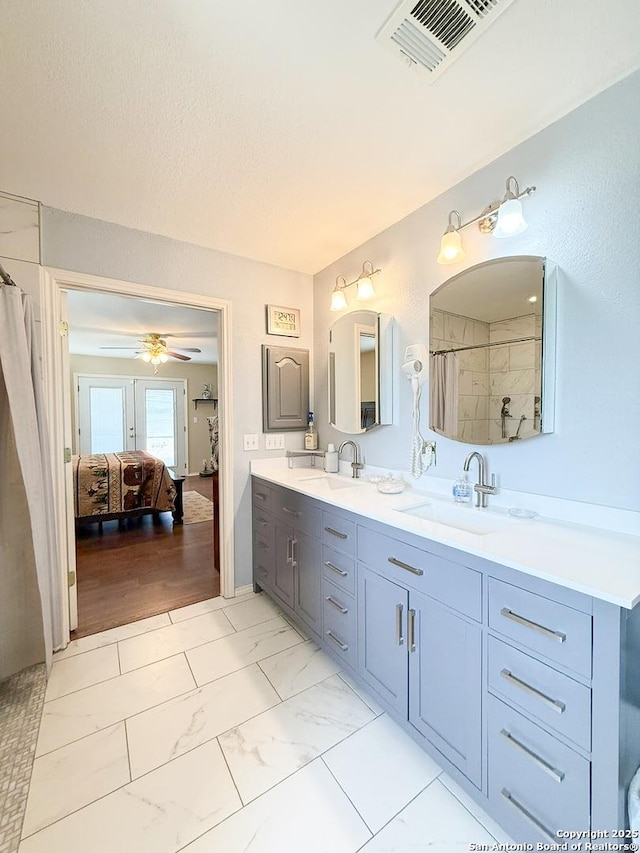 1185 County Road 7718, Devine, TX 78016 - ensuite bathroom featuring double vanity, ceiling fan, marble look tiles, and curtained shower