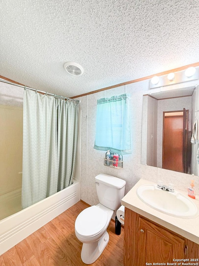 1185 County Road 7718, Devine, TX 78016 - full bath with a textured ceiling, wood finished floors, shower / bath combo, toilet, and vanity