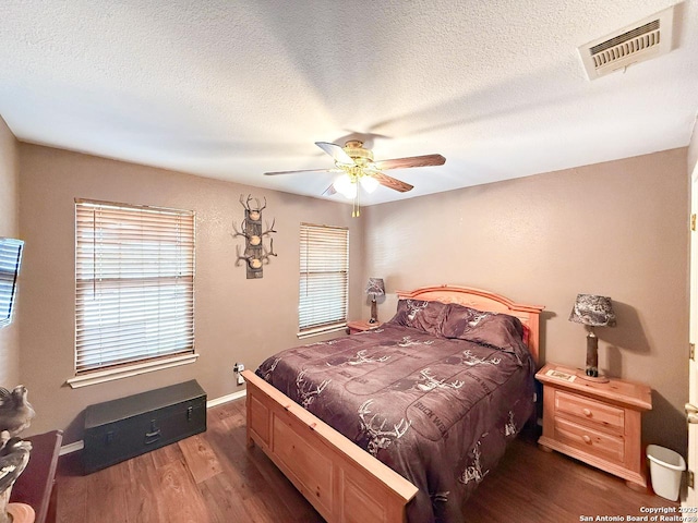 1185 County Road 7718, Devine, TX 78016 - bedroom featuring wood finished floors, a textured ceiling, ceiling fan, and baseboards