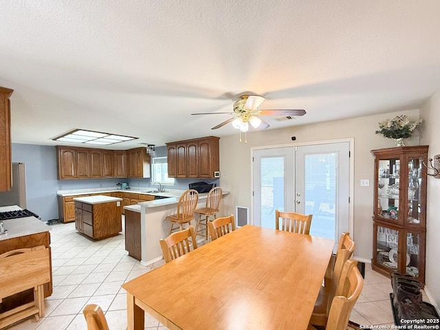 1185 County Road 7718, Devine, TX 78016 - dining room featuring light tile patterned floors, french doors, ceiling fan, and a textured ceiling