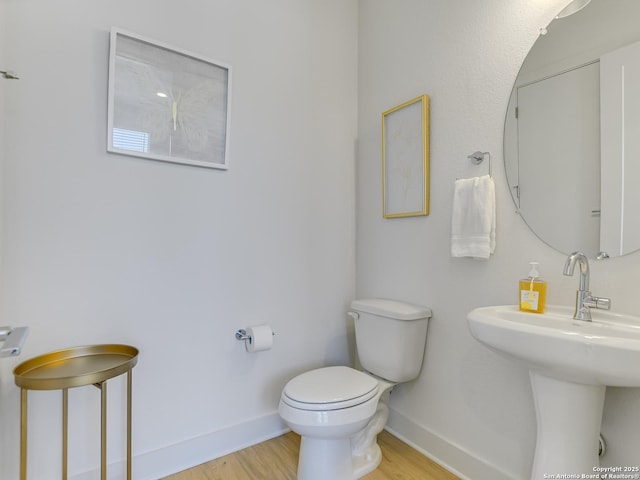 2050 Lohmans Spur Unit, Lakeway, TX 78734 - half bath featuring toilet, baseboards, wood finished floors, and a sink