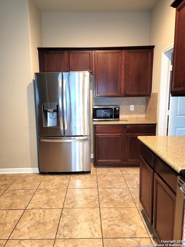 26106 Indian Clf, San Antonio, TX 78260 - kitchen featuring appliances with stainless steel finishes, light stone counters, tasteful backsplash, baseboards, and light tile patterned floors