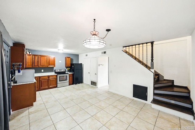 7122 Brecon, San Antonio, TX 78239 - kitchen with freestanding refrigerator, electric stove, brown cabinetry, light countertops, and light tile patterned flooring