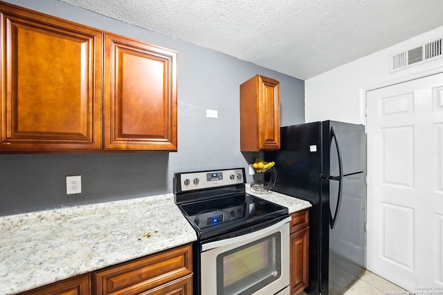 7122 Brecon, San Antonio, TX 78239 - kitchen with stainless steel electric stove, freestanding refrigerator, a textured ceiling, brown cabinetry, and light stone countertops
