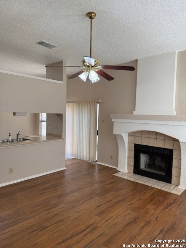 6210 Valley Clf, San Antonio, TX 78250 - unfurnished living room with ceiling fan, a sink, wood finished floors, a tile fireplace, and a textured ceiling