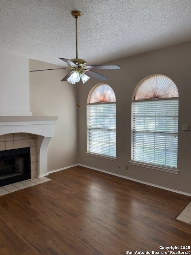6210 Valley Clf, San Antonio, TX 78250 - unfurnished living room with ceiling fan, wood finished floors, a textured ceiling, a tile fireplace, and baseboards