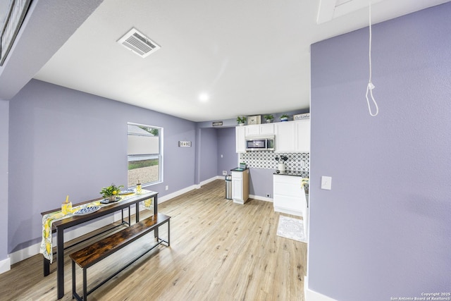 1437 Avant, San Antonio, TX 78210 - kitchen featuring stainless steel microwave, white cabinetry, light wood-style flooring, and baseboards
