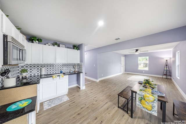 1437 Avant, San Antonio, TX 78210 - kitchen with stainless steel microwave, tasteful backsplash, light wood finished floors, white cabinetry, and a ceiling fan