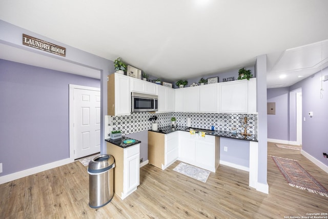 1437 Avant, San Antonio, TX 78210 - kitchen with stainless steel microwave, decorative backsplash, light wood-style flooring, baseboards, and white cabinets