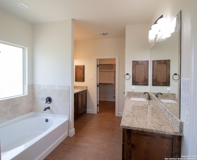 2516 County Road 357, La Vernia, TX 78121 - full bath with vanity, wood finished floors, a bath, a spacious closet, and baseboards