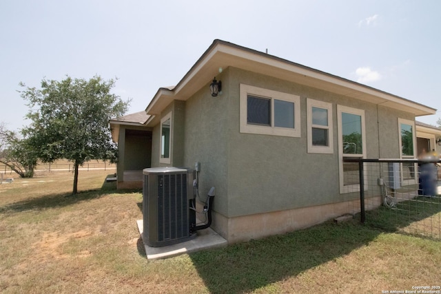 2516 County Road 357, La Vernia, TX 78121 - view of property exterior with central AC unit, a lawn, and stucco siding