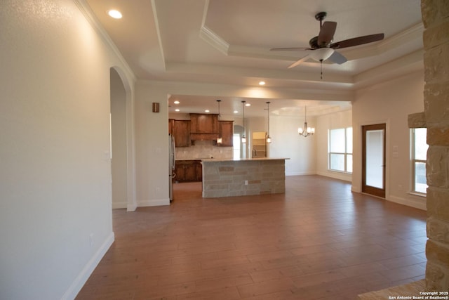 2516 County Road 357, La Vernia, TX 78121 - unfurnished living room with a ceiling fan, arched walkways, a chandelier, a raised ceiling, and ornamental molding
