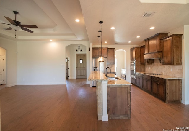 2516 County Road 357, La Vernia, TX 78121 - kitchen with arched walkways, a sink, backsplash, a ceiling fan, and stainless steel appliances