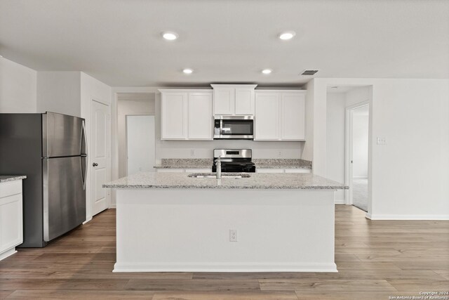 14923 Telfaire Mdw, Von Ormy, TX 78073 - kitchen with appliances with stainless steel finishes, a sink, white cabinets, a kitchen island with sink, and light stone counters