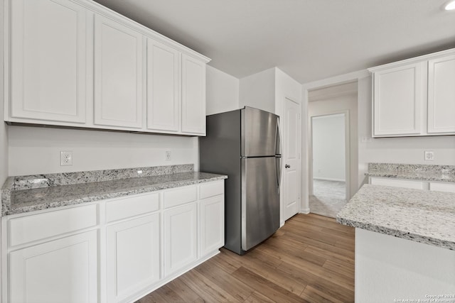 14923 Telfaire Mdw, Von Ormy, TX 78073 - kitchen featuring freestanding refrigerator, white cabinets, light wood-type flooring, and light stone countertops