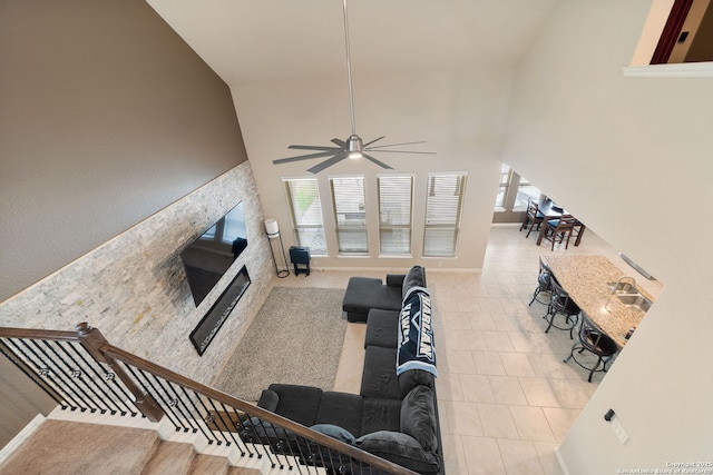 8726 Hideout, San Antonio, TX 78254 - tiled living area featuring a stone fireplace, ceiling fan, high vaulted ceiling, and a sink