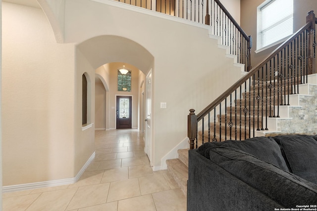 8726 Hideout, San Antonio, TX 78254 - entryway with a towering ceiling, arched walkways, light tile patterned flooring, stairs, and baseboards