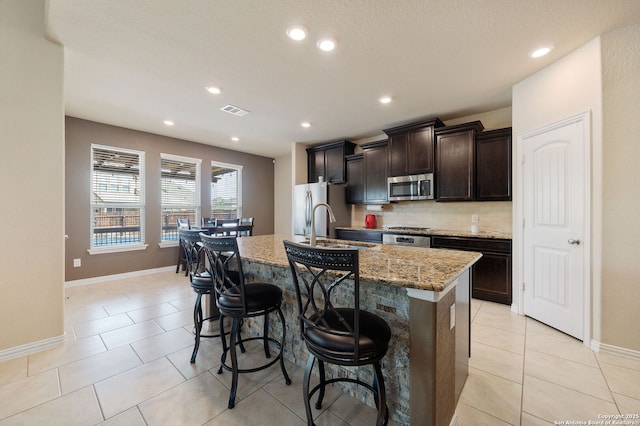8726 Hideout, San Antonio, TX 78254 - kitchen featuring stainless steel appliances, a kitchen island with sink, a breakfast bar area, backsplash, and a sink