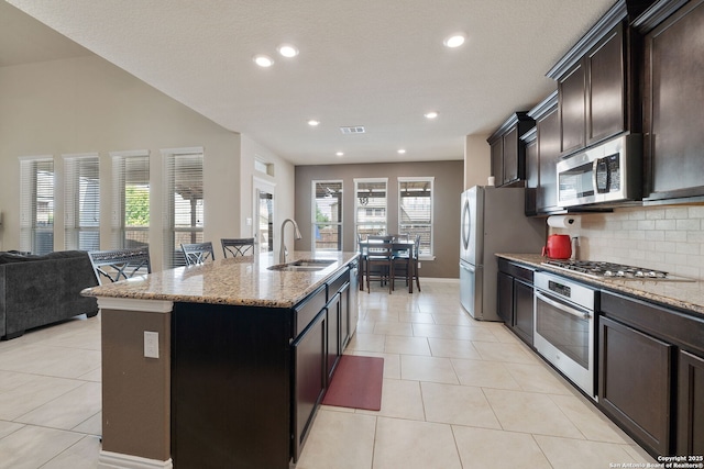 8726 Hideout, San Antonio, TX 78254 - kitchen with appliances with stainless steel finishes, a sink, a center island with sink, open floor plan, and light stone countertops