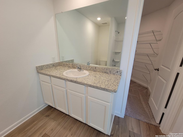 15107 Telfaire Mdw, Von Ormy, TX 78073 - bathroom with wood finished floors, vanity, baseboards, recessed lighting, and toilet