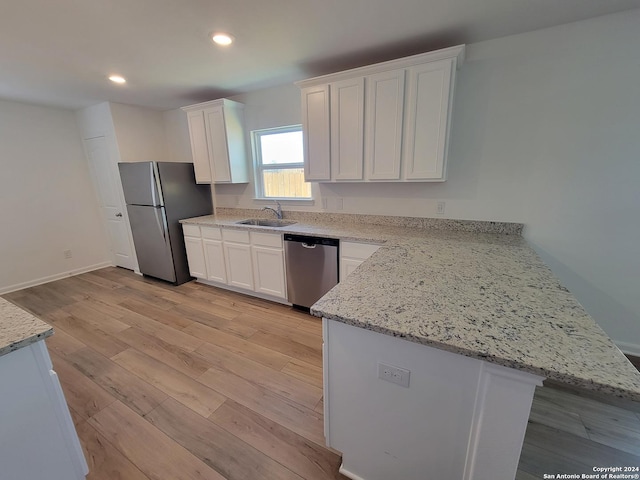 15107 Telfaire Mdw, Von Ormy, TX 78073 - kitchen with appliances with stainless steel finishes, a sink, white cabinets, light wood-style flooring, and a peninsula
