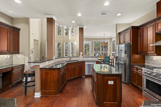 7414 Hovingham, San Antonio, TX 78257 - kitchen with appliances with stainless steel finishes, a kitchen island, decorative backsplash, a breakfast bar area, and recessed lighting