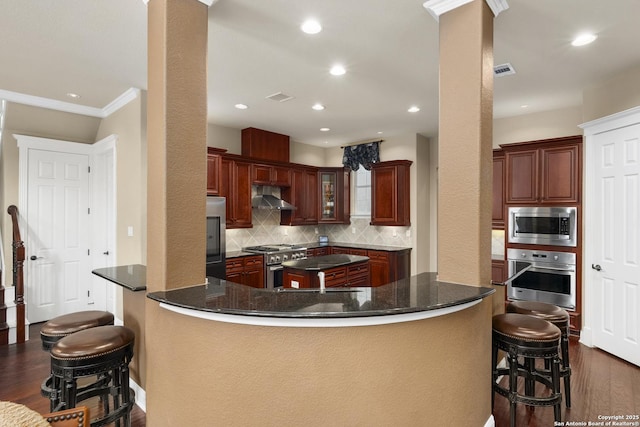 7414 Hovingham, San Antonio, TX 78257 - kitchen with appliances with stainless steel finishes, wall chimney exhaust hood, dark wood finished floors, backsplash, and a kitchen breakfast bar