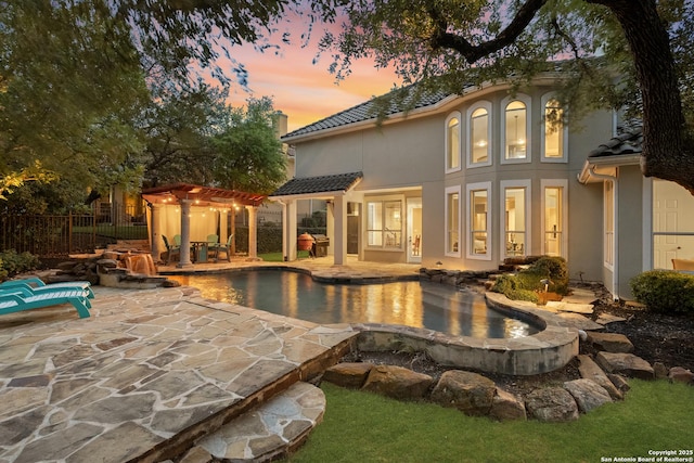 7414 Hovingham, San Antonio, TX 78257 - back of property at dusk featuring stucco siding, a tiled roof, a pergola, and a patio