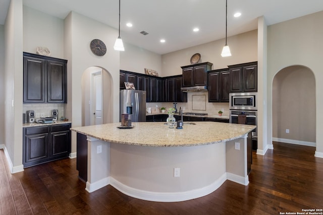 364 Stone Trl, Castroville, TX 78009 - kitchen featuring arched walkways, stainless steel appliances, backsplash, dark wood-style floors, and a large island with sink