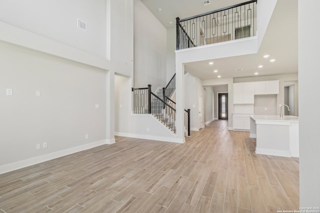 29414 Angelfish Blvd, Boerne, TX 78006 - unfurnished living room featuring a high ceiling, baseboards, light wood finished floors, stairs, and recessed lighting