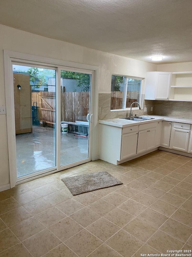 1336 Churing, San Antonio, TX 78245 - kitchen featuring a sink, white cabinetry, open shelves, light countertops, and decorative backsplash