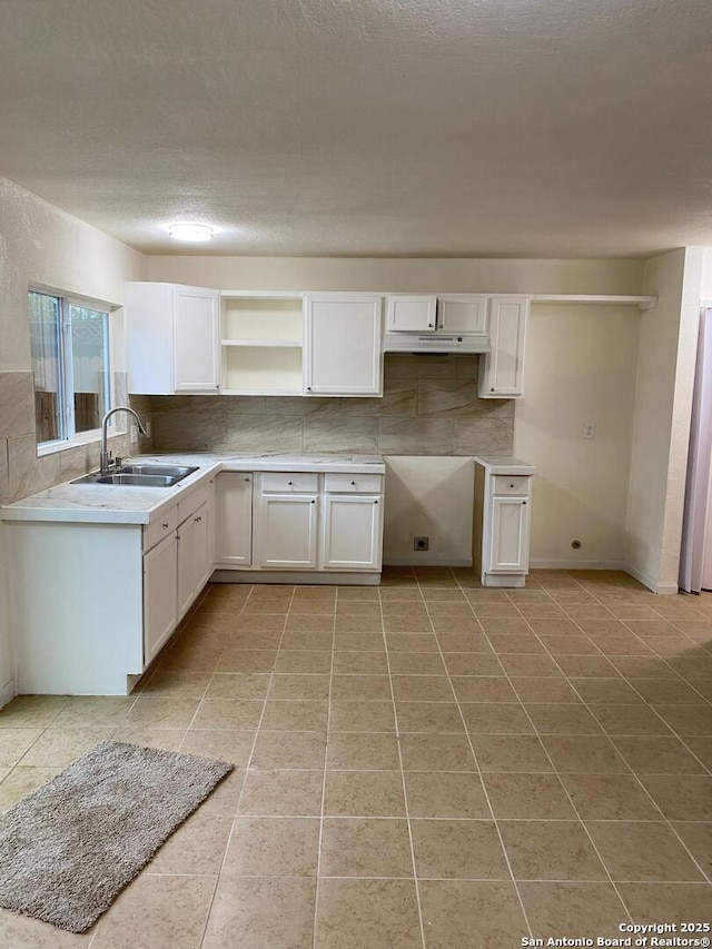 1336 Churing, San Antonio, TX 78245 - kitchen with a sink, under cabinet range hood, light tile patterned floors, decorative backsplash, and a textured ceiling