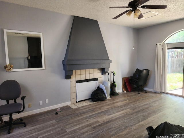 2960 Ash Fld, San Antonio, TX 78245 - office featuring wood finished floors, a textured ceiling, ceiling fan, baseboards, and a tiled fireplace