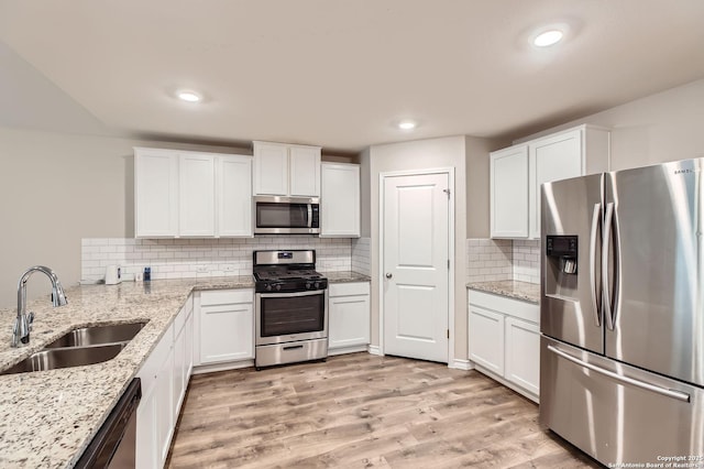 4811 Tee Box Ct, San Antonio, TX 78261 - kitchen featuring appliances with stainless steel finishes, a sink, white cabinetry, tasteful backsplash, and light wood-style floors