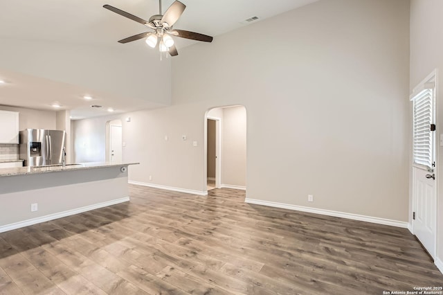 4811 Tee Box Ct, San Antonio, TX 78261 - unfurnished living room with high vaulted ceiling, arched walkways, ceiling fan, wood finished floors, and baseboards