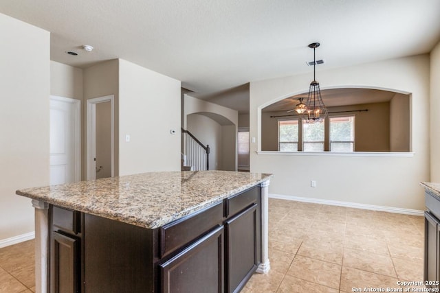 27511 Smokey Chase, Boerne, TX 78015 - kitchen featuring arched walkways, dark brown cabinets, light tile patterned floors, hanging light fixtures, and baseboards