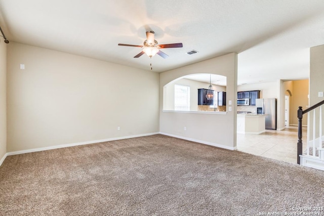 27511 Smokey Chase, Boerne, TX 78015 - unfurnished living room with light carpet, a ceiling fan, baseboards, stairs, and arched walkways