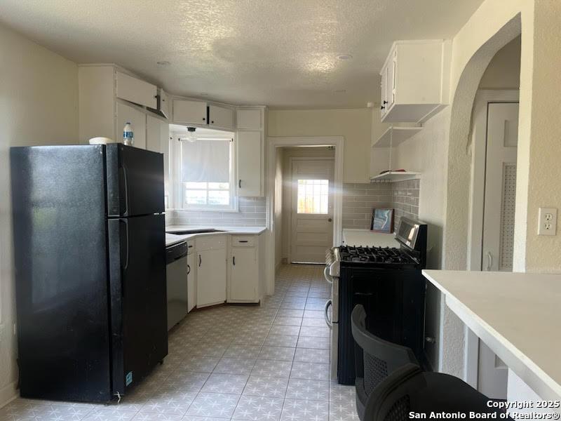 389 Meredith, San Antonio, TX 78228 - kitchen featuring stainless steel appliances, light countertops, white cabinetry, arched walkways, and a textured ceiling