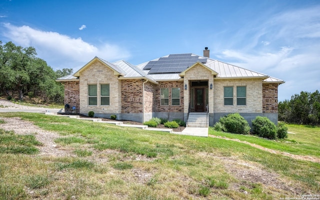 1015 Broken Spoke, Canyon Lake, TX 78133 - view of front of home with a standing seam roof, roof mounted solar panels, metal roof, a front yard, and a chimney