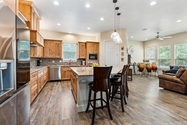 1015 Broken Spoke, Canyon Lake, TX 78133 - kitchen with appliances with stainless steel finishes, wood finished floors, open floor plan, a kitchen island, and recessed lighting