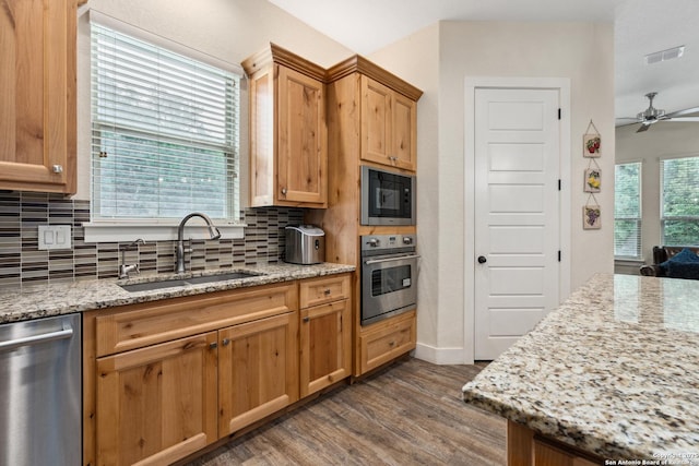 1015 Broken Spoke, Canyon Lake, TX 78133 - kitchen with appliances with stainless steel finishes, a sink, dark wood-type flooring, decorative backsplash, and a ceiling fan