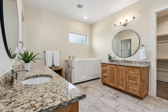 1015 Broken Spoke, Canyon Lake, TX 78133 - bathroom with two vanities, a tub to relax in, a walk in closet, and recessed lighting
