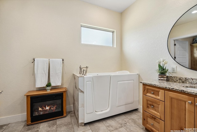 1015 Broken Spoke, Canyon Lake, TX 78133 - bathroom with vanity, a bath, baseboards, and a glass covered fireplace