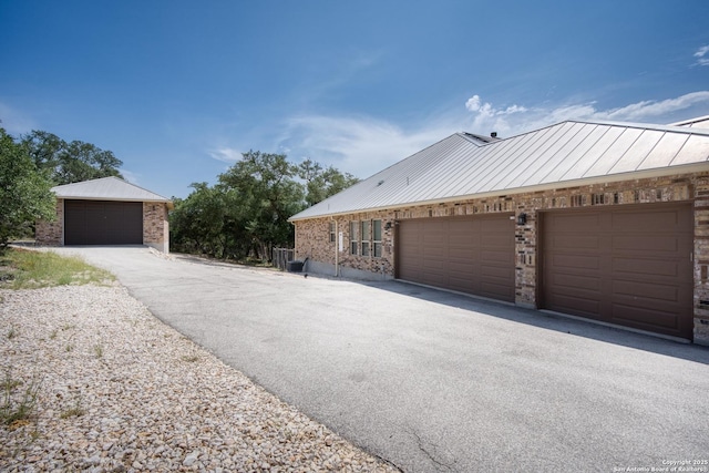 1015 Broken Spoke, Canyon Lake, TX 78133 - view of side of home with brick siding, metal roof, a standing seam roof, and a garage