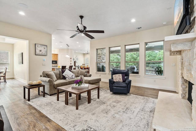 1015 Broken Spoke, Canyon Lake, TX 78133 - living area with wood finished floors, a ceiling fan, a fireplace, baseboards, and recessed lighting