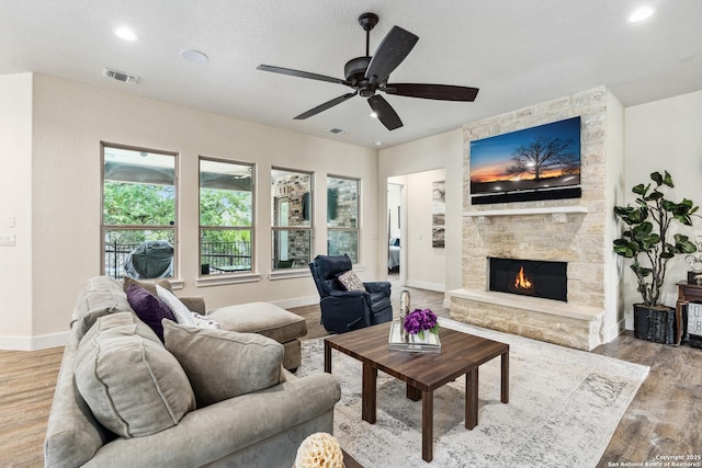 1015 Broken Spoke, Canyon Lake, TX 78133 - living area featuring wood finished floors, a stone fireplace, a ceiling fan, baseboards, and recessed lighting