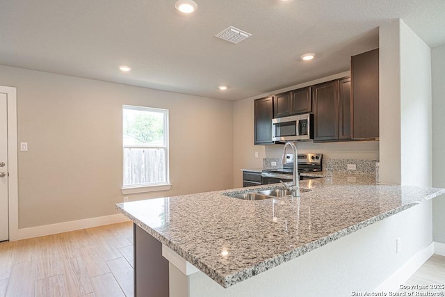 324 Mar Hl, Seguin, TX 78155 - kitchen featuring stainless steel appliances, light stone counters, dark brown cabinets, baseboards, and a peninsula