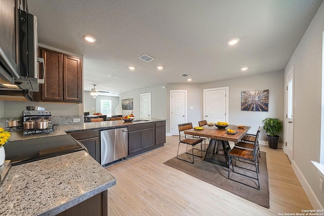 324 Mar Hl, Seguin, TX 78155 - kitchen with dark brown cabinetry, recessed lighting, fridge, a peninsula, and light wood-style floors