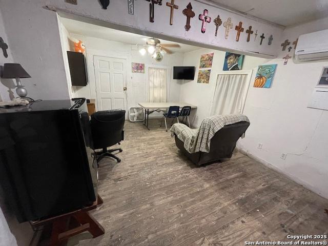 261 San Gabriel, San Antonio, TX 78237 - living area featuring an AC wall unit, wood finished floors, and a ceiling fan